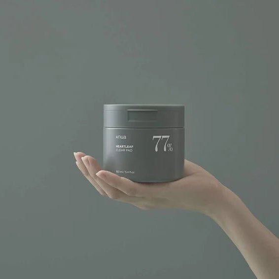 Hand holding a gray container with '77%' on a dark background