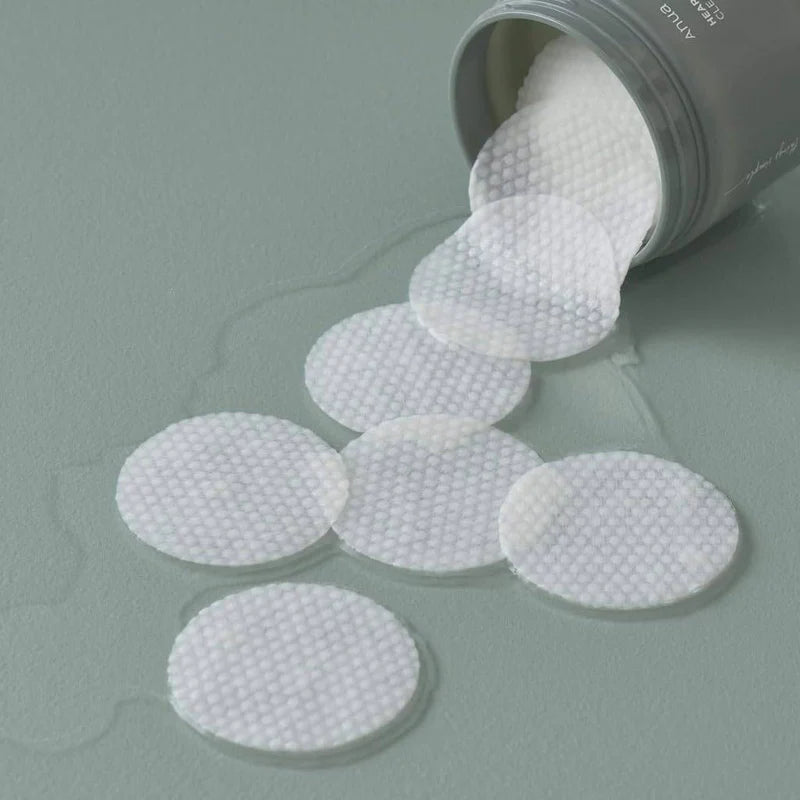 White circular absorbent pads spilling out of a container on a gray surface