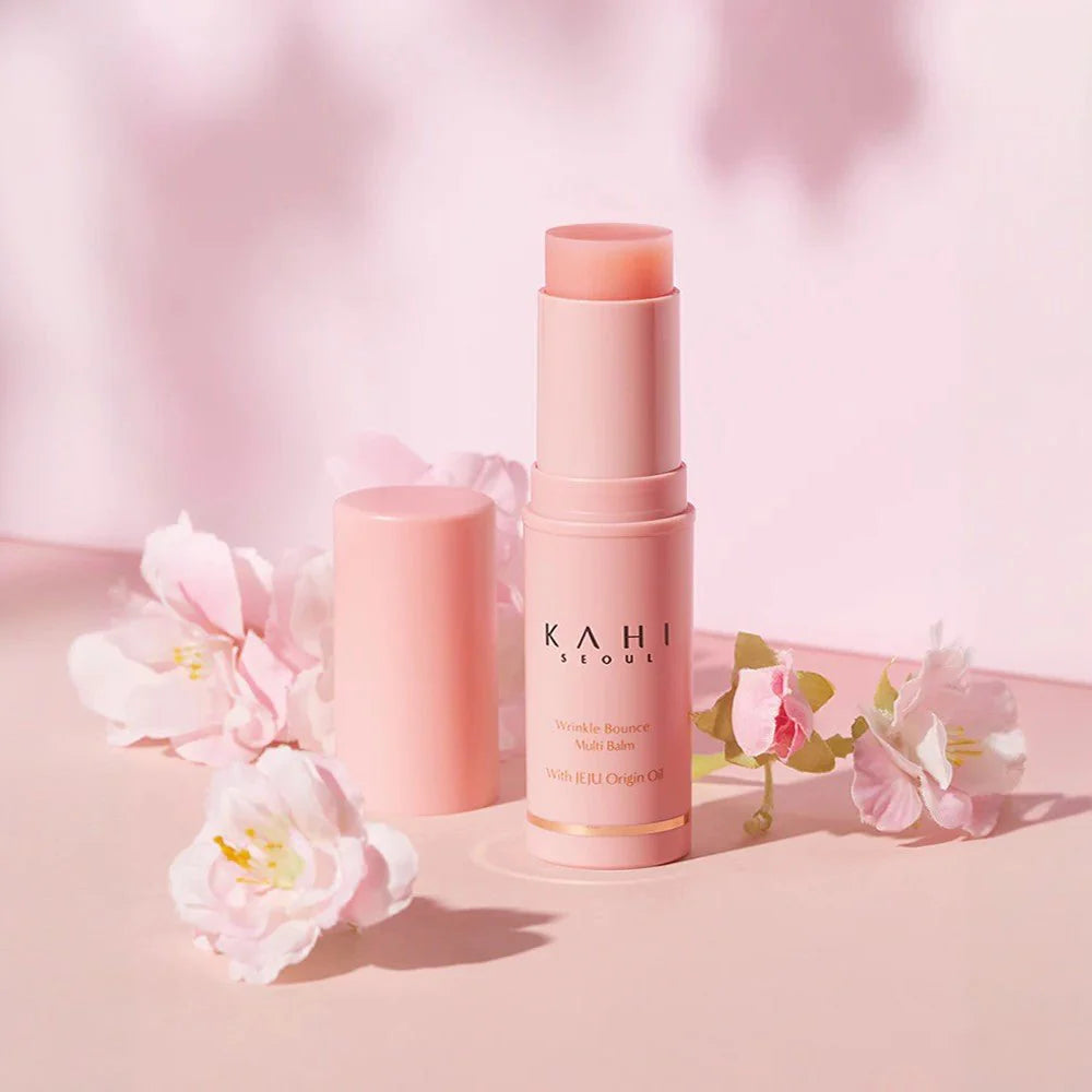 Two pink lip balms with 'KAHI' branding on a soft pink background with flowers.